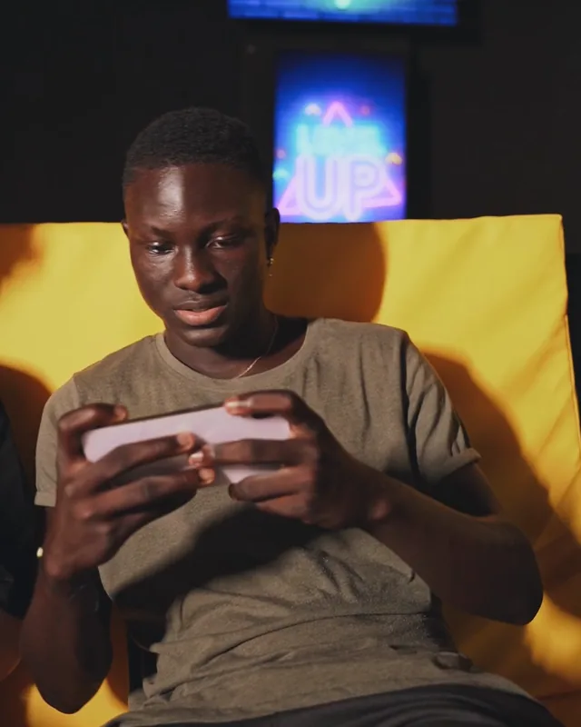 A man playing a mobile game under neon signs