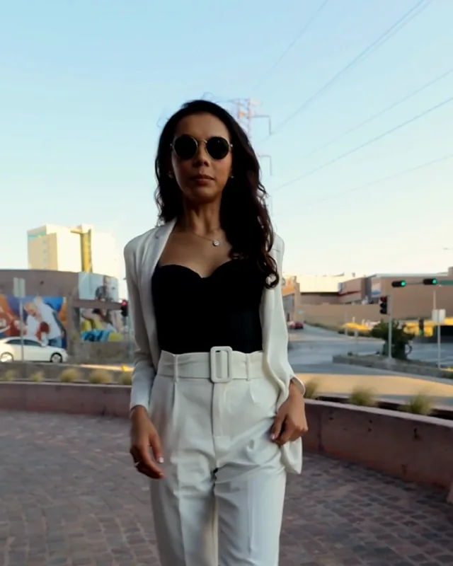 A woman in a white suit and sunglasses on a city street