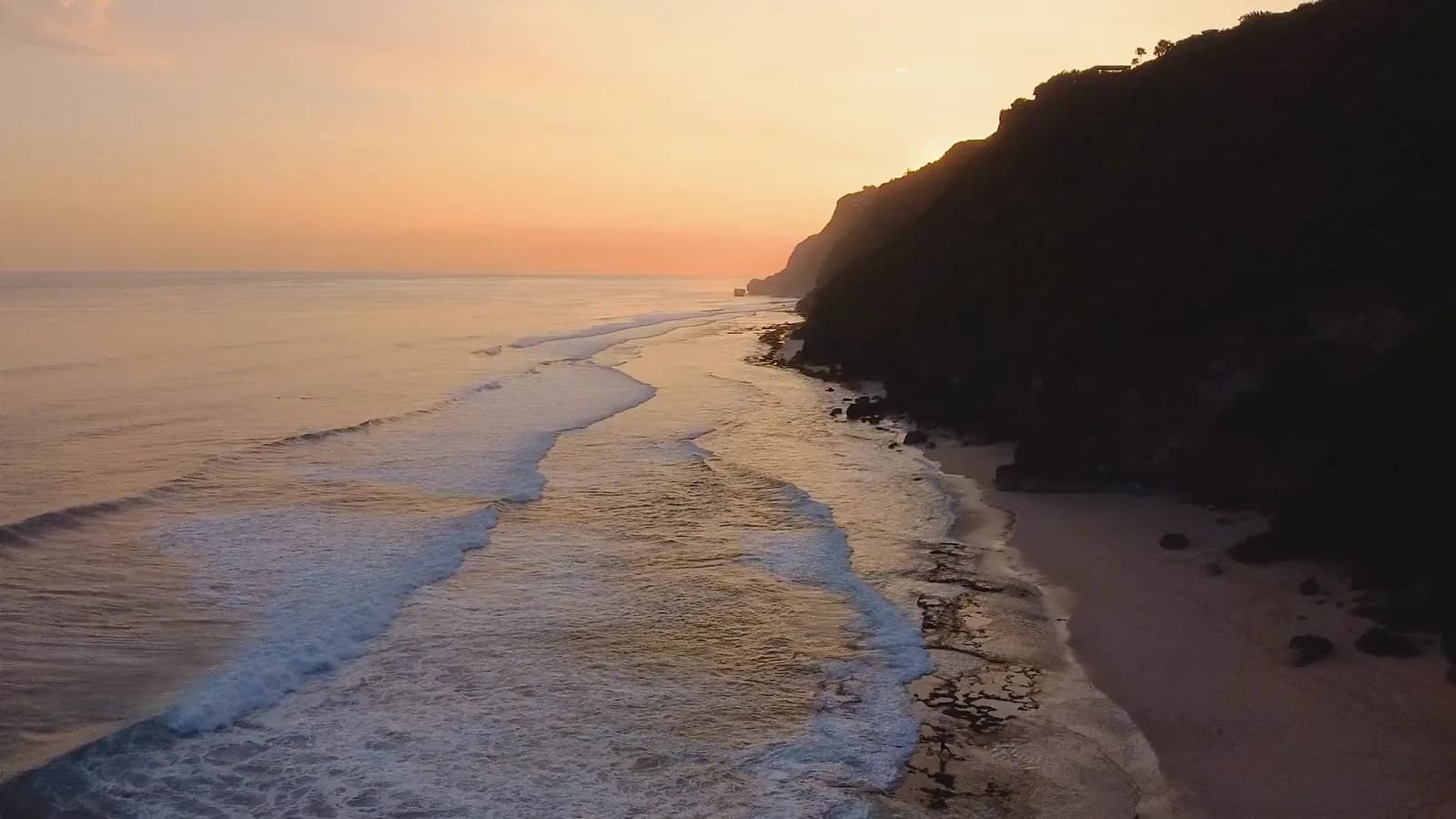 An aerial shot of a coastline at sunset