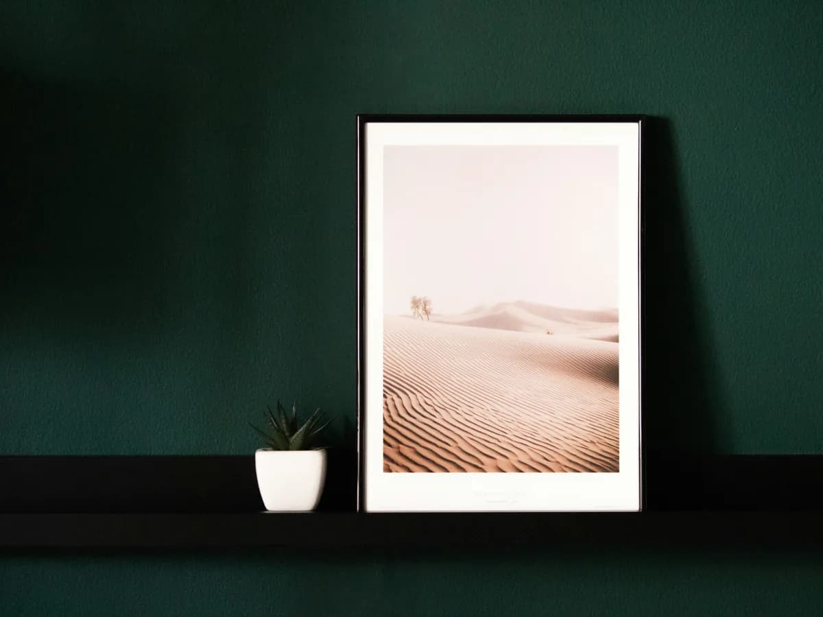 A framed print against a dark green wall