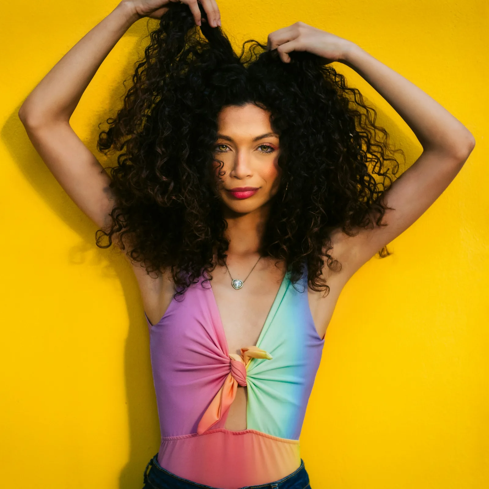 A woman with curly hair against a yellow wall