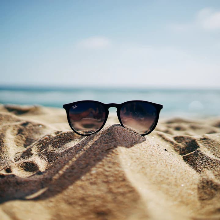 Sunglasses on sand, key visual