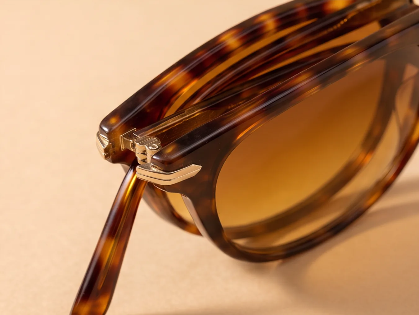 A pair of tortoiseshell sunglasses on a sand backdrop, from a new angle