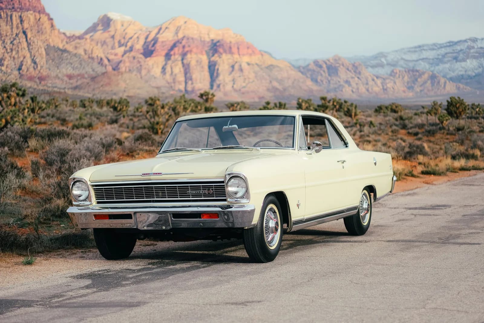 A cream classic car on a desert road