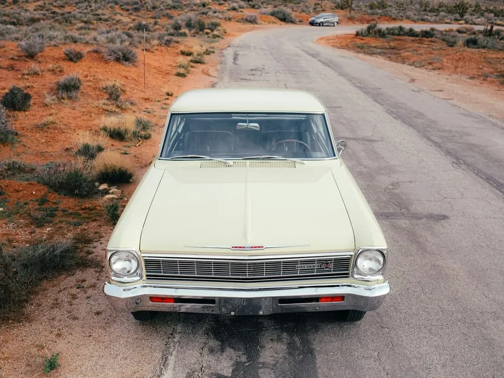 A classic car on a desert road, facing the camera
