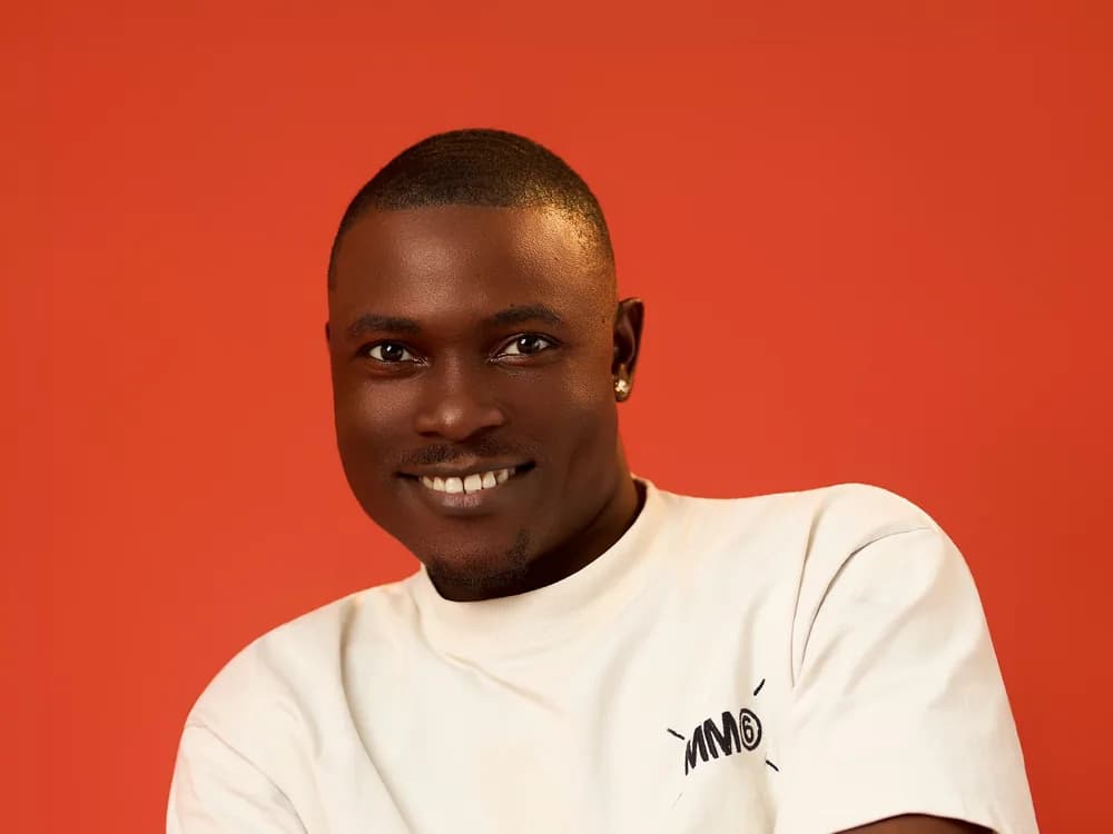 A man smiling against an orange backdrop