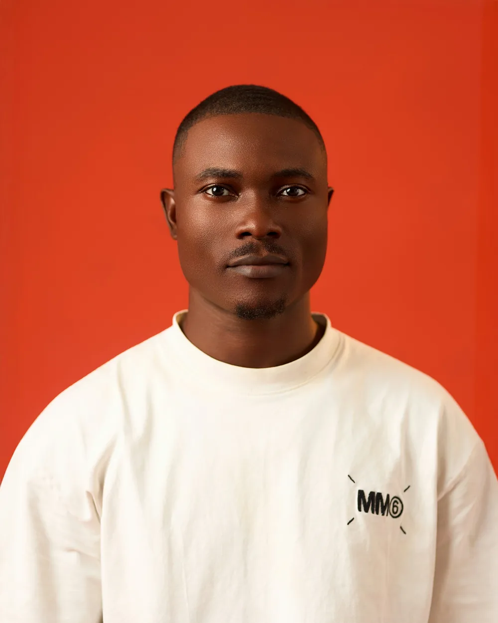 A man standing against an orange backdrop