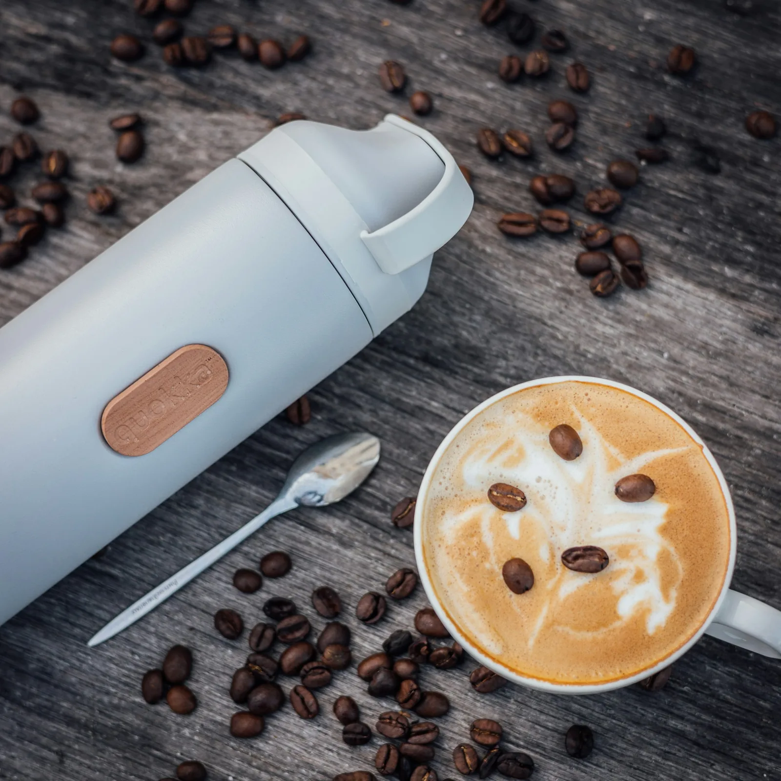 A thermos and a latte on a wooden table