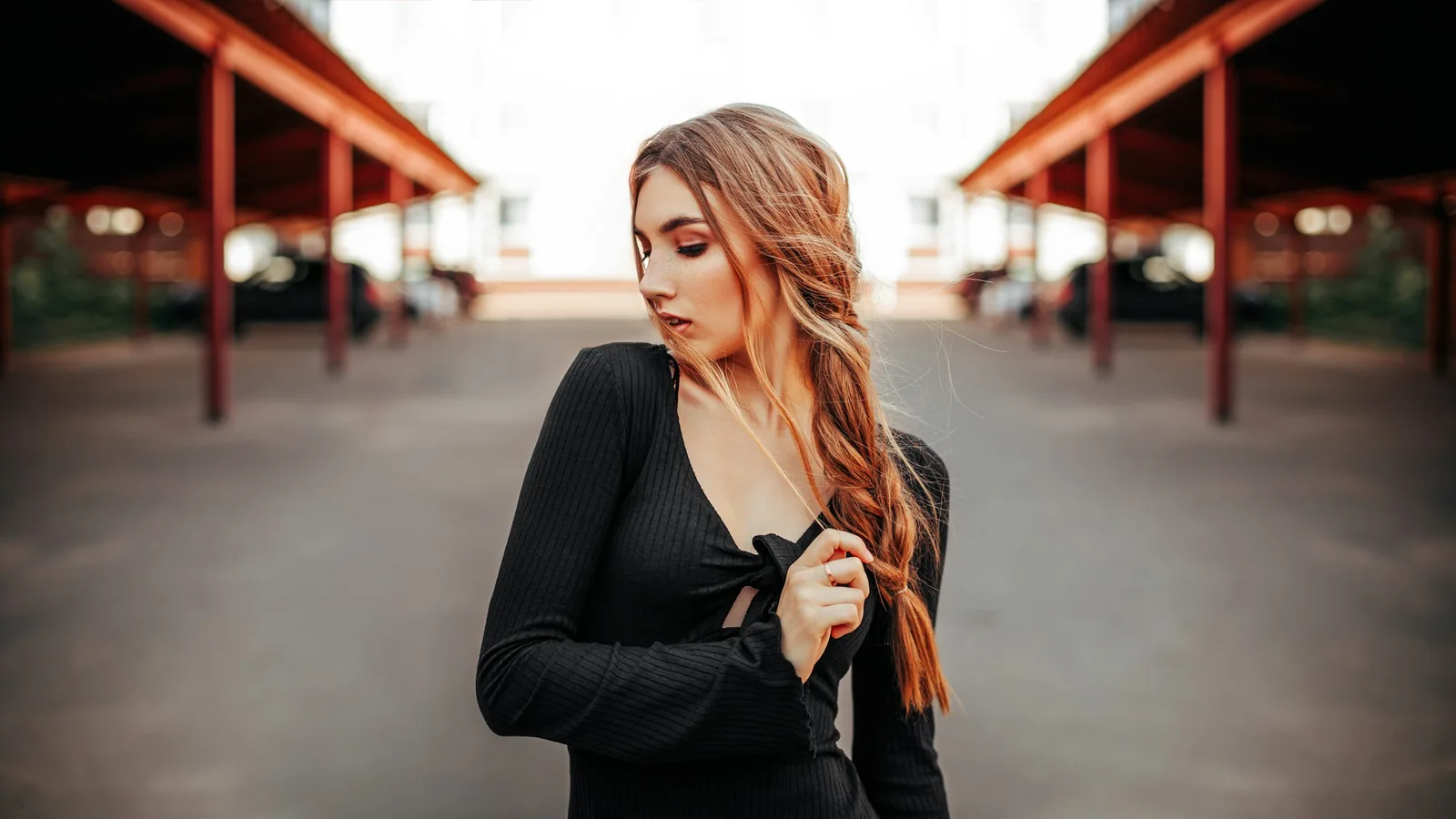 A woman in black with long copper hair under red canopies