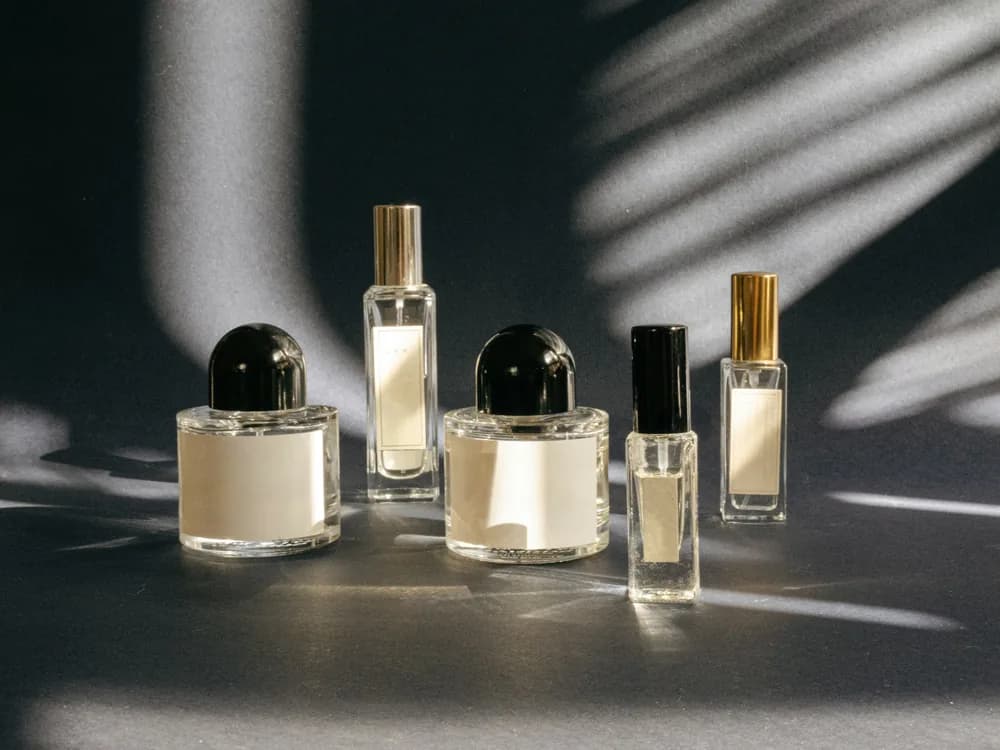 Perfume bottles of different heights under palm shadows