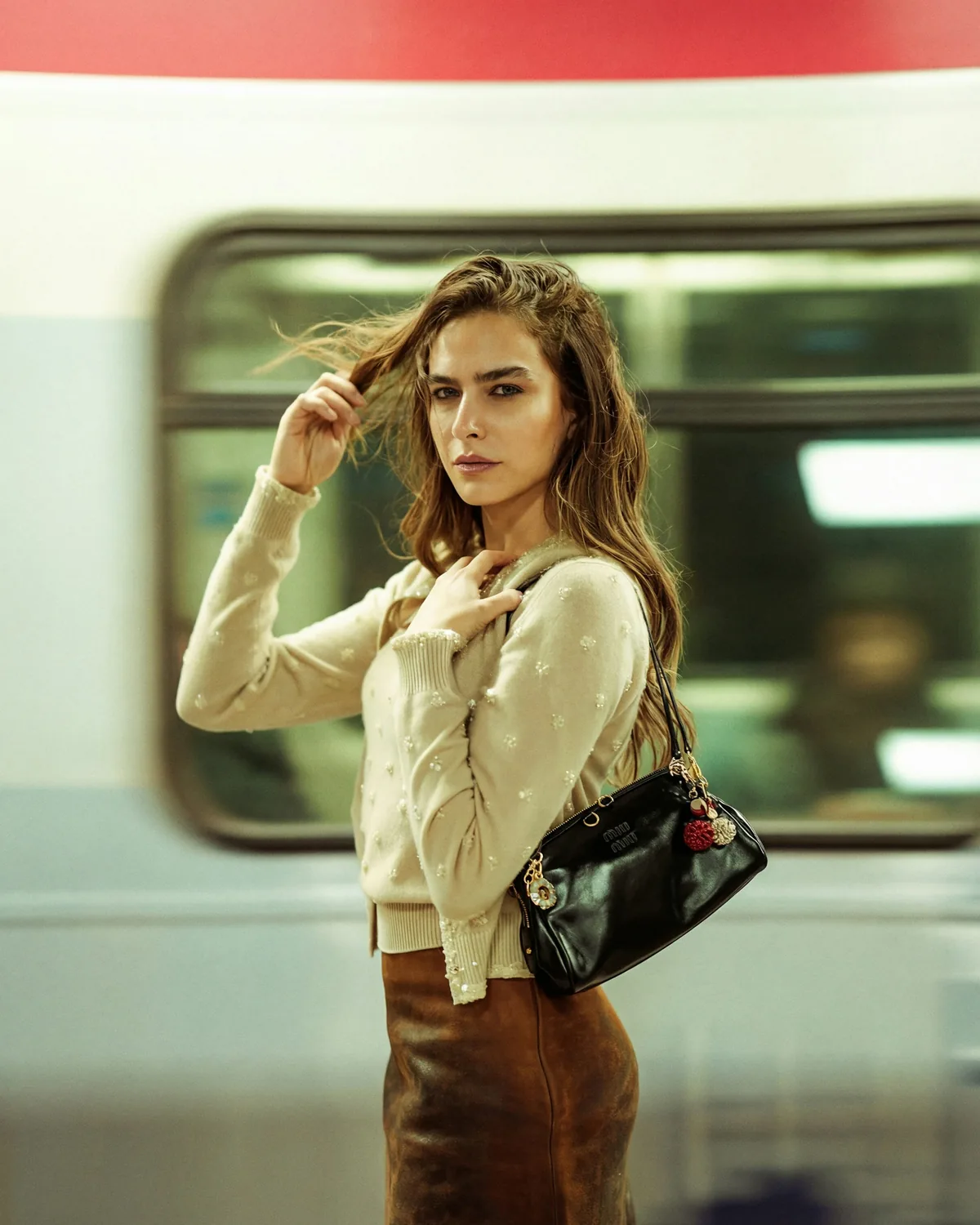 The woman with the black handbag on a metro platform as a train passes