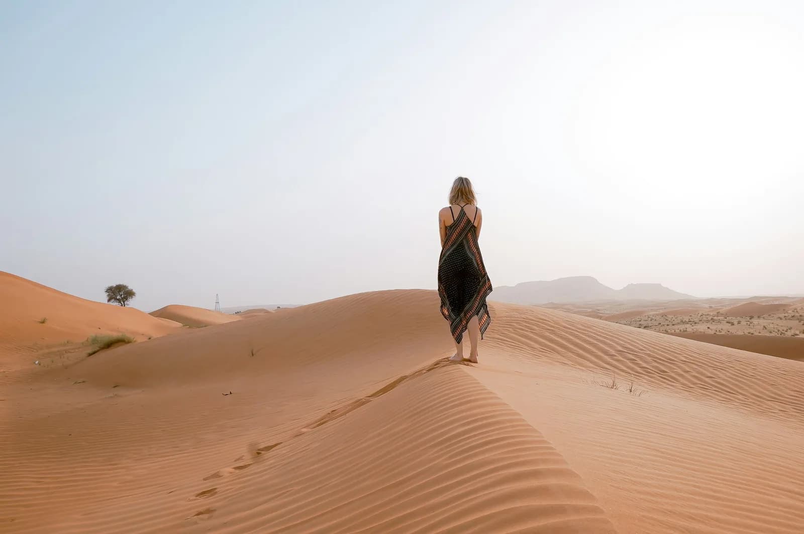 A woman walking the crest of a sand dune at dawn