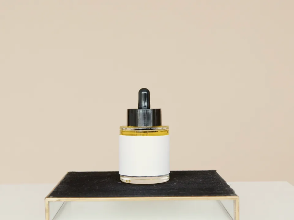 A serum bottle on a black plinth against beige