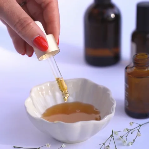 A dropper over a bowl of amber oil