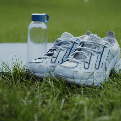 Running shoes and a water bottle on the grass