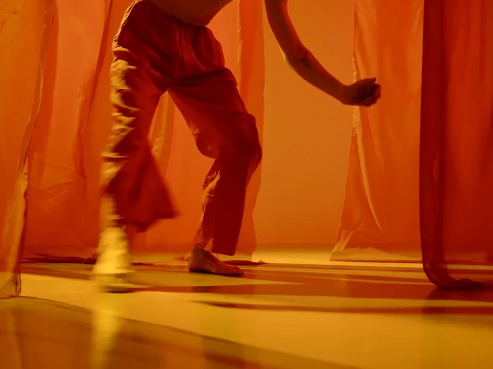 A dancer between orange curtains