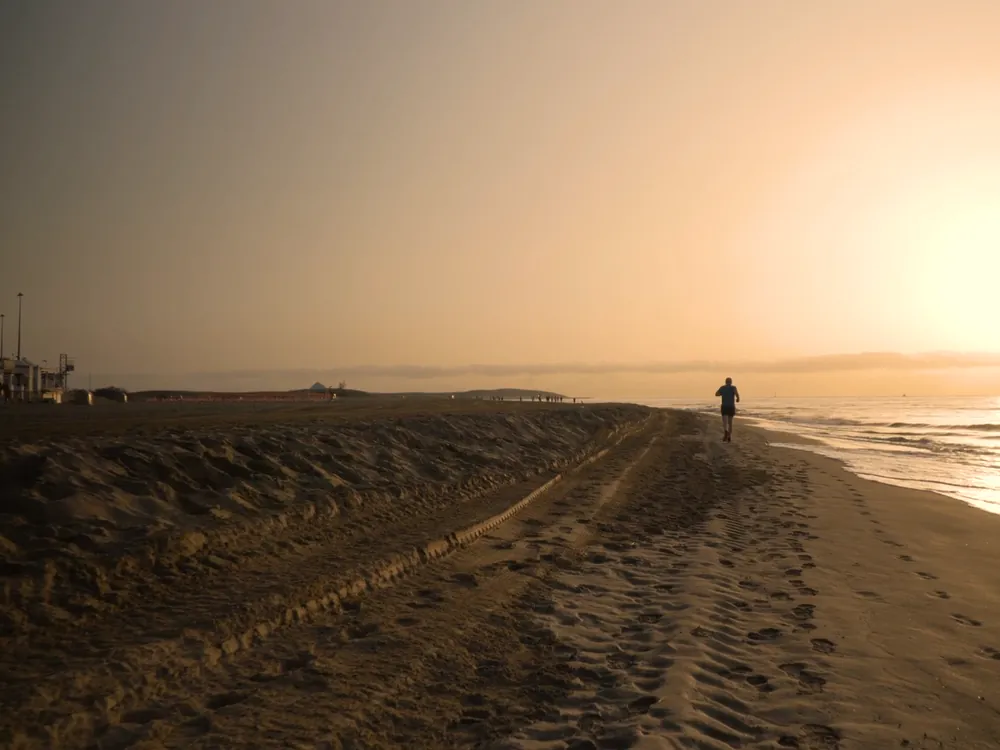 A runner on the shore in golden haze