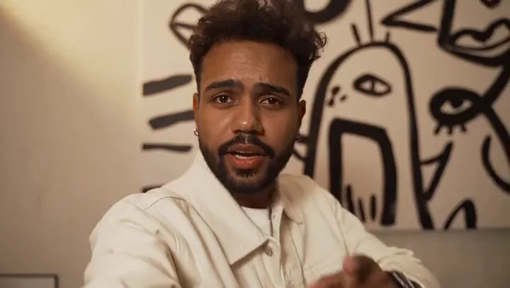 A creator talking to camera in front of a mural