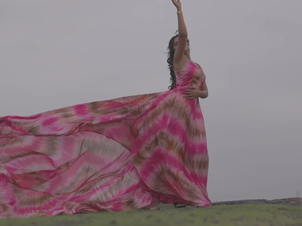 A woman in a long pink dress caught by the wind