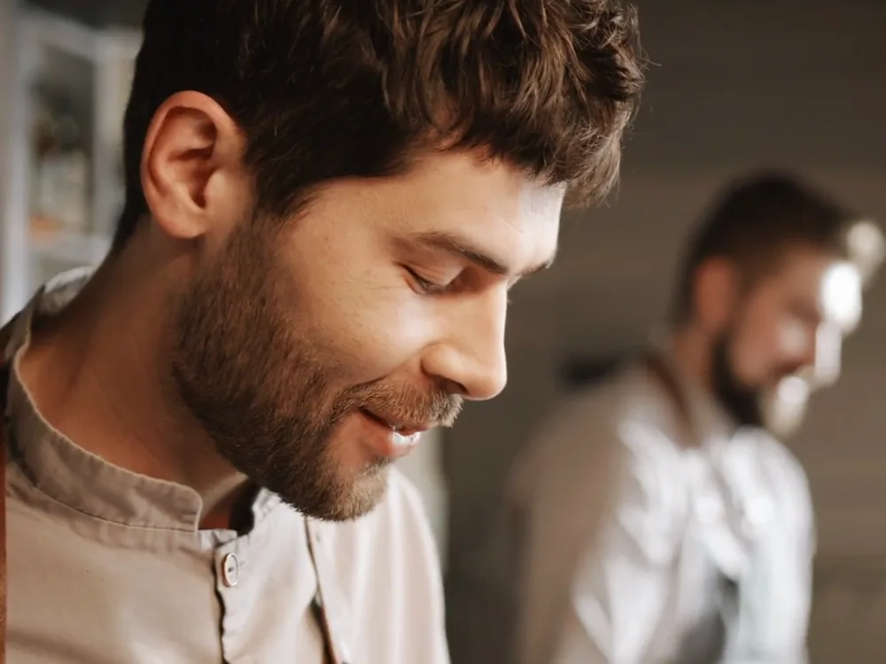 A cook smiling down at the counter in a kitchen