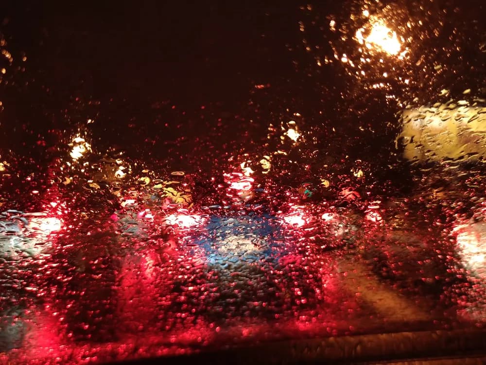 Tail lights blurred through a rainy windshield at night
