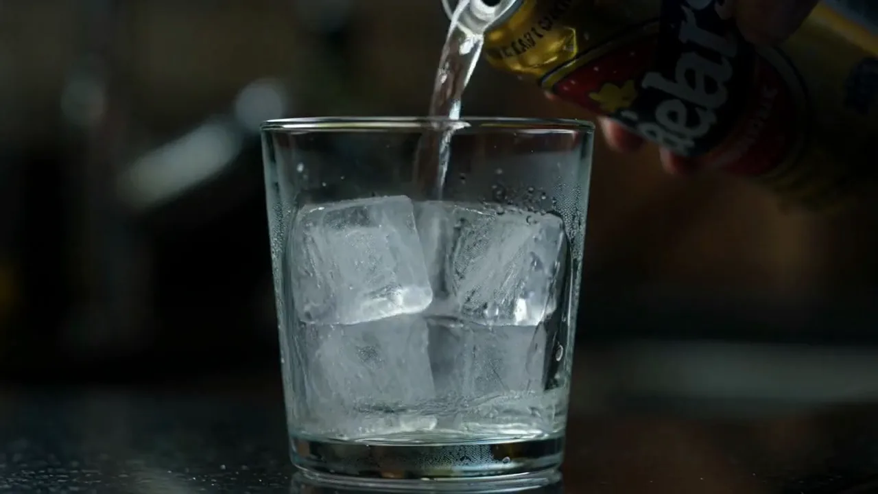 A glass of ice with a can pouring into it