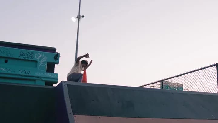 A skater on top of a box at a skate park against a pale sky