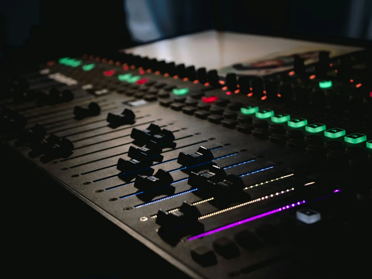 A lit mixing console in a dark studio