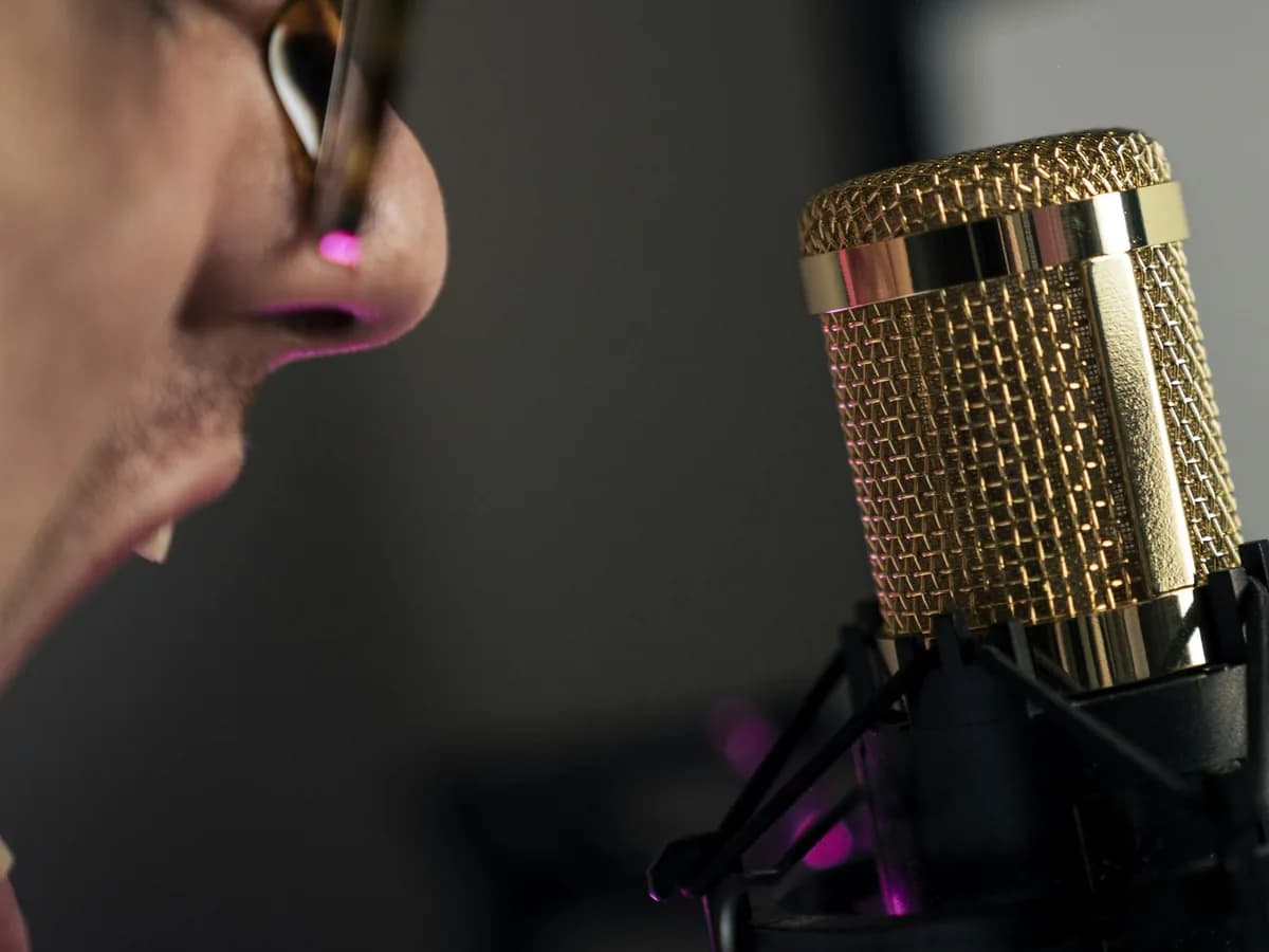 A man speaking into a gold studio microphone