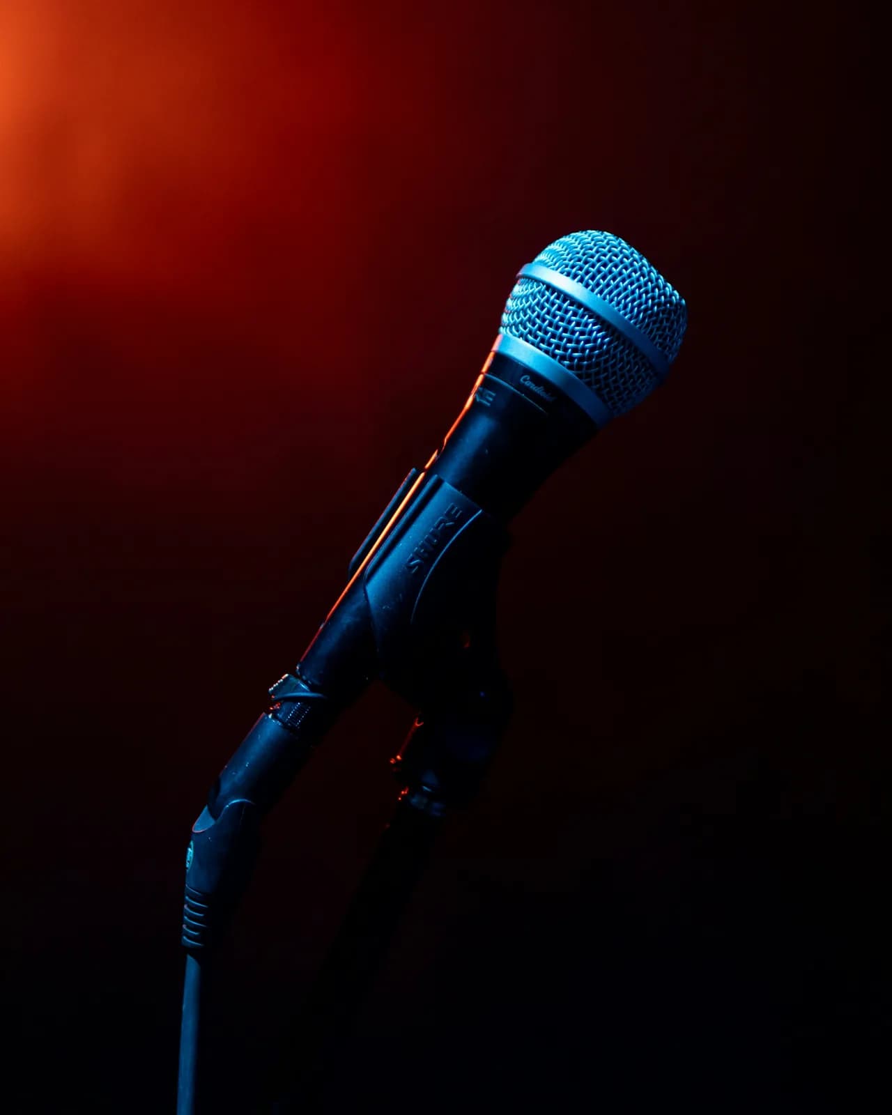 A blue microphone on a stand against a red wall